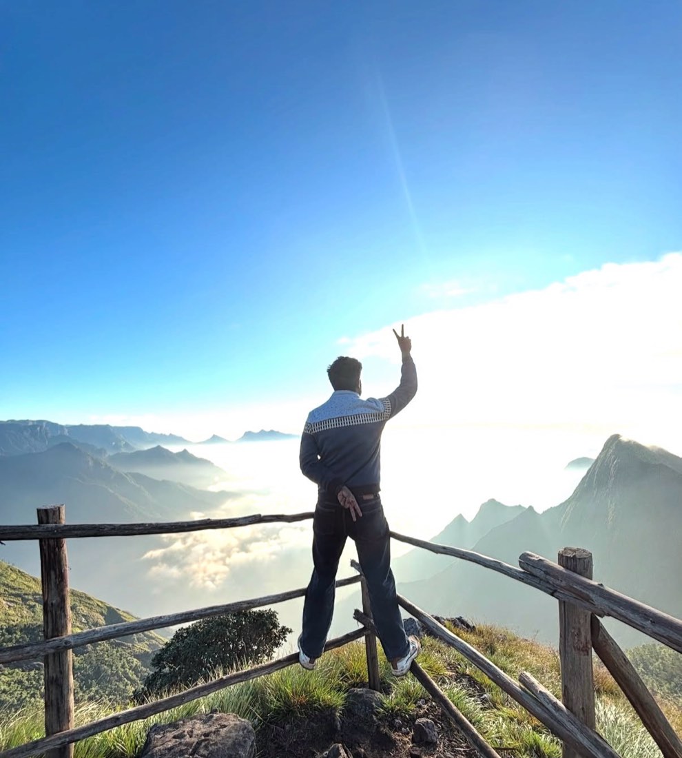 A trekker at the Kolukkumalai viewpoint above the clouds